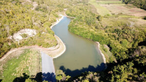 Photo en vue aérienne du site du projet agrivoltaïque de Grand Bassin à Marie- Galante. On y voit un cours d'eau et de la végétation.